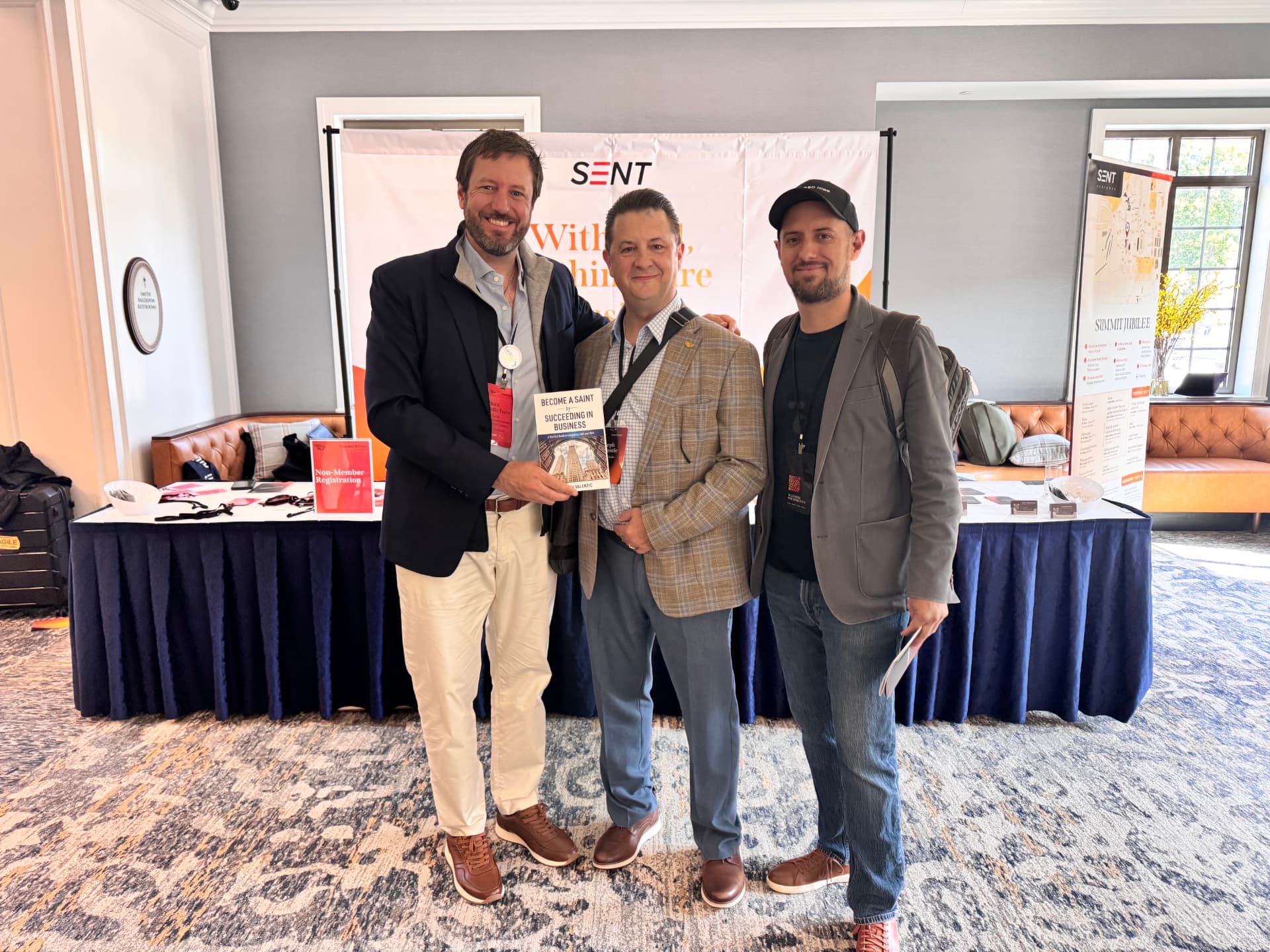 Joe Valentic with attendees holding his book Become a Saint by Succeeding in Business